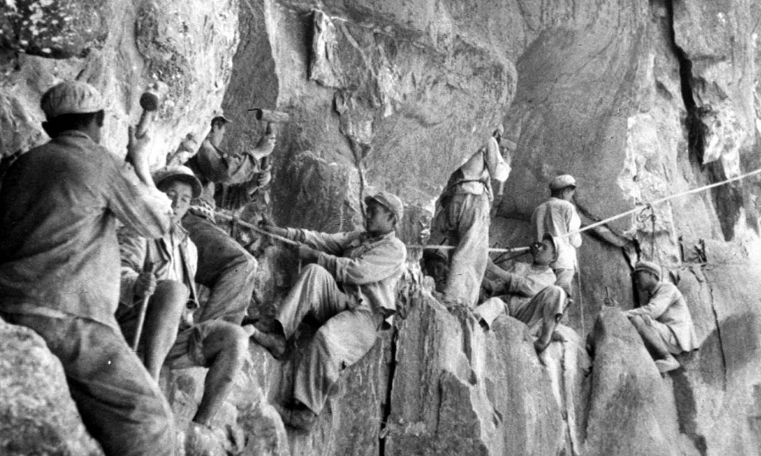 1954年，修筑康藏公路的解放軍戰(zhàn)士們在怒江兩岸的懸崖陡壁上辟山筑路。新華社稿 李萬春、張加里攝